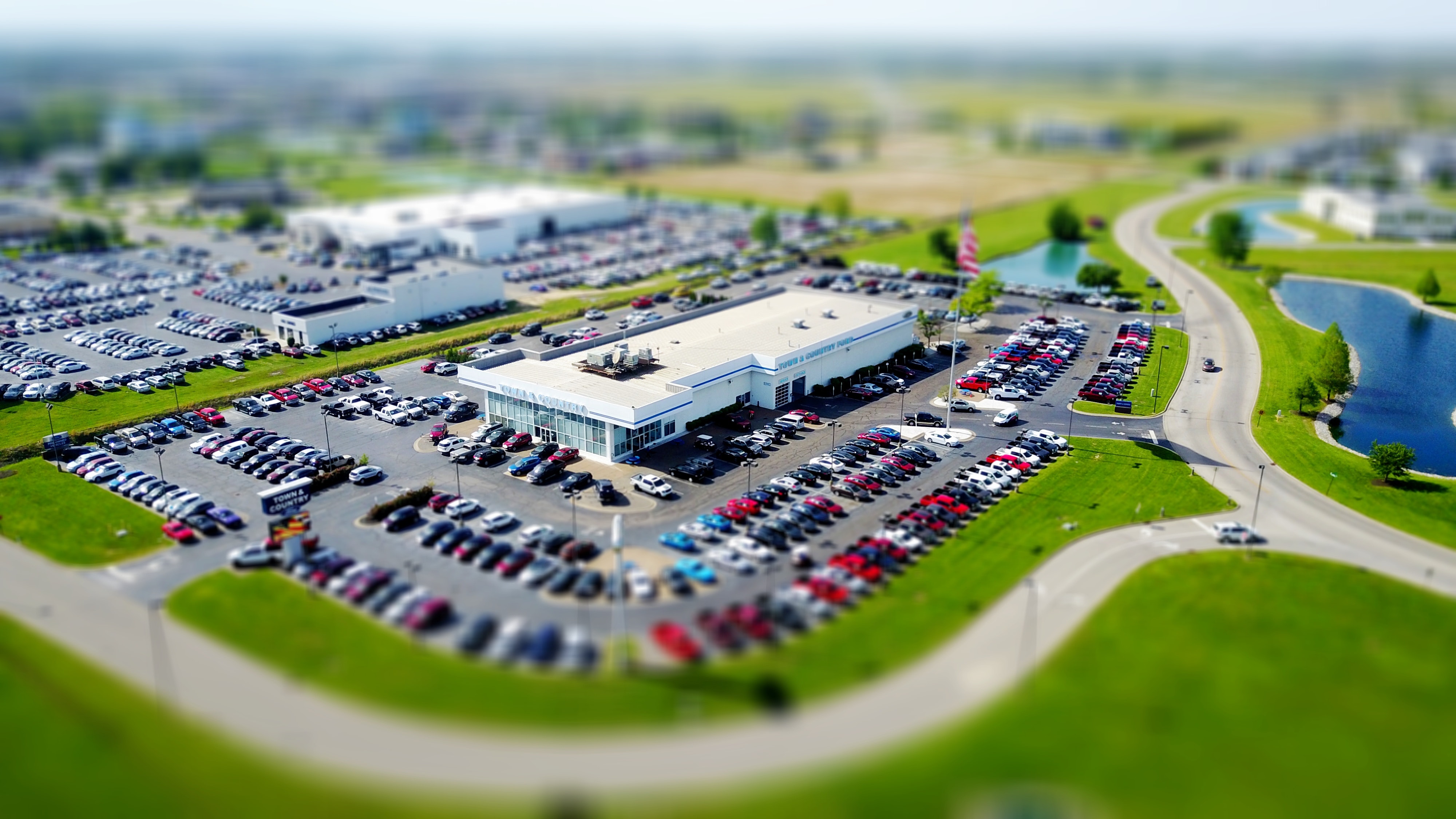 A car dealership surrounded by roads and fields.