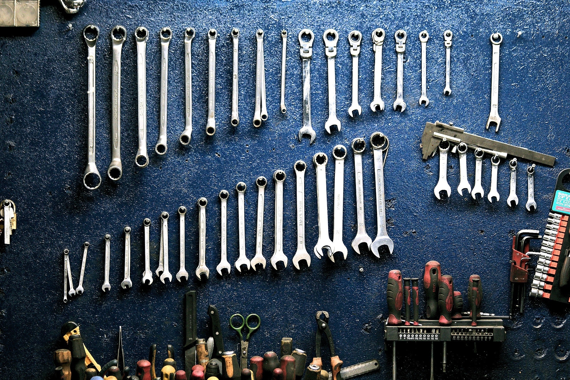 A set of car mechanics' tools hang on the wall of a mechanic's workspace.
